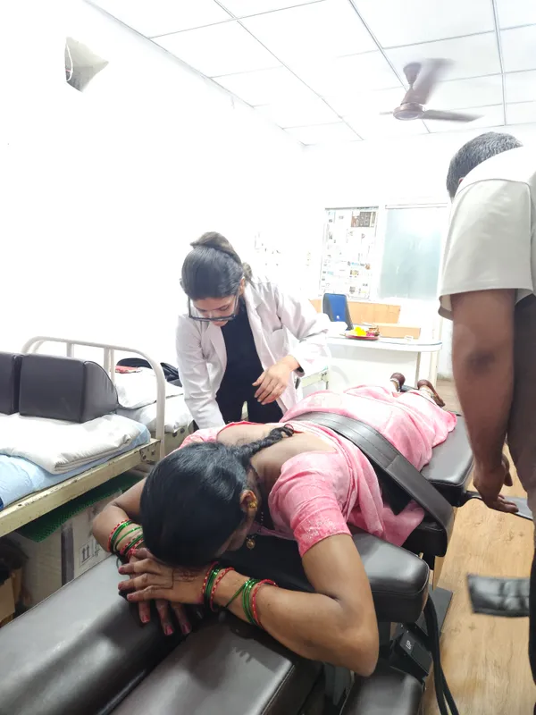 Person positioned face down on the spine decompression table with a support belt and assistance beside the table.